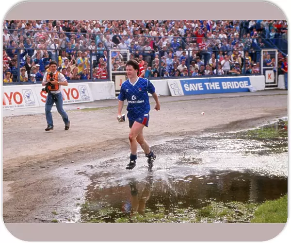Kevin McAllister of Chelsea runs through the puddles with the Division Two trophy