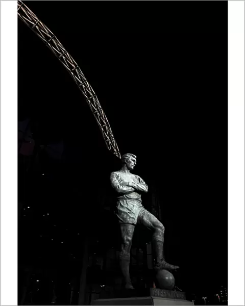 The Bobby Moore statue stands in front of an illuminated Wembley Stadium