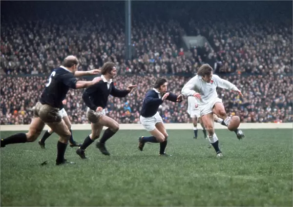 Englands Peter Warfield kicks ahead under pressure from Scotlands Ian McGeechan - 1975 5 Nations