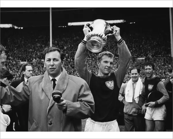 West Ham captain Bobby Moore lifts the FA Cup next to David Coleman in 1964