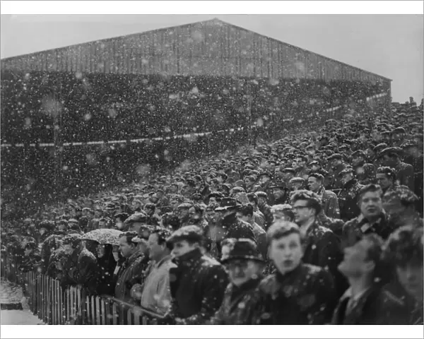 Fans at Old Trafford watch the action in the snow during the 1954  /  5 FA Cup