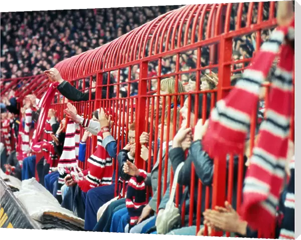Manchester United fans hold their scarves through fences at the Stretford End in 1977