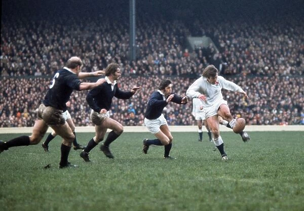 Englands Peter Warfield kicks ahead under pressure from Scotlands Ian McGeechan - 1975 5 Nations