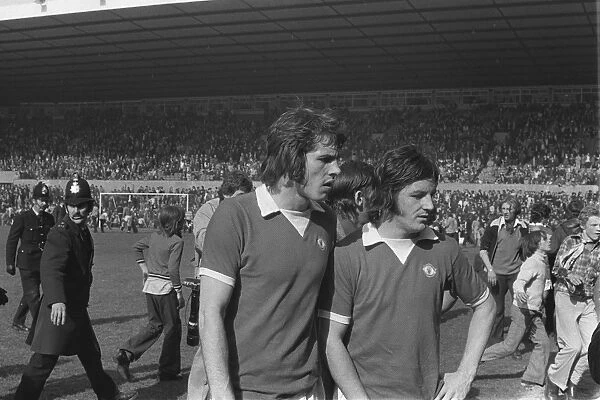 Manchester Uniteds Jim Holton and Alex Forsyth leave the field after United fans invade the Old Trafford pitch in 1974