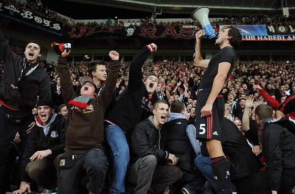 + Manuel Friedrich of Leverkusen leads the fans in celebration with a megaphone after their dramatic last minute victory over Chelsea