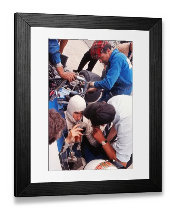 Framed Print : Jackie Stewart has a drink while his mechanics examine the car during practice at the 1969 British Grand Prix Framed Print : Jackie Stewart has a drink while his mechanics examine the car during practice at the 1969 British Grand Prix