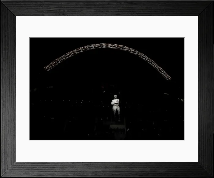 Framed Print : The statue of Bobby Moore stands in front of an illuminated Wembley Stadium Framed Print : The statue of Bobby Moore stands in front of an illuminated Wembley Stadium