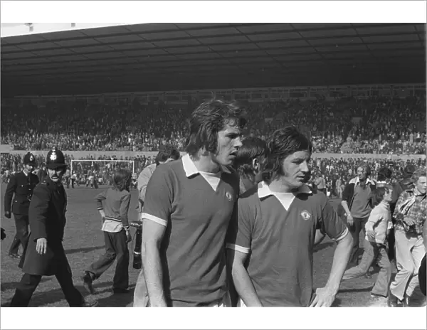 Manchester Uniteds Jim Holton and Alex Forsyth leave the field after United fans invade the Old Trafford pitch in 1974