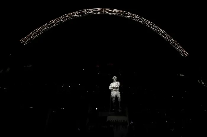Framed Print : The statue of Bobby Moore stands in front of an illuminated Wembley Stadium Framed Print : The statue of Bobby Moore stands in front of an illuminated Wembley Stadium