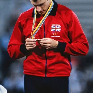 Allan Wells inspects his 100m gold medal on the podium at the 1980 Moscow Olympics