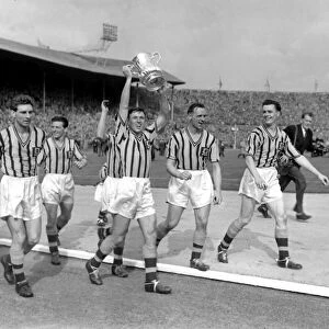 Aston Villa captain Johnny Dixon leads his side on a victory lap with the FA Cup trophy in 1957