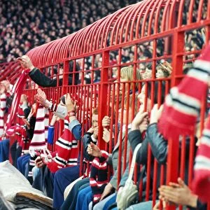 Manchester United fans hold their scarves through fences at the Stretford End in 1977