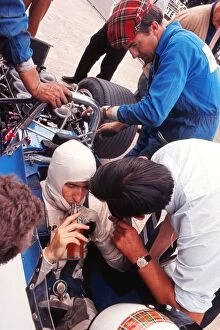 Images Dated 24th March 2011: Jackie Stewart has a drink while his mechanics examine the car during practice at the 1969 British