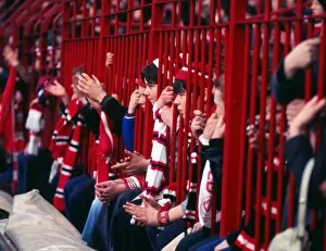Images Dated 18th February 2013: Manchester United fans hold their scarves through fences at the Stretford End in 1977