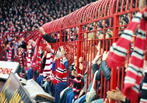 Manchester United fans hold their scarves through fences at the Stretford End in 1977