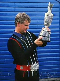 Images Dated 7th July 2011: Sandy Lyle examines the Claret Jug while wearing a replica of the original Championship Belt in 1985