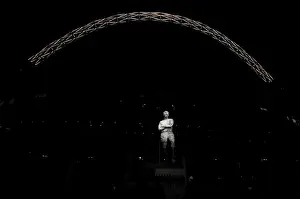 Images Dated 15th November 2011: The statue of Bobby Moore stands in front of an illuminated Wembley Stadium